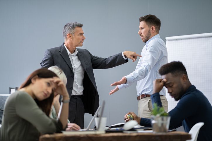 Group Of Businesspeople Looking At Businessman Blaming His Colleague In Meeting