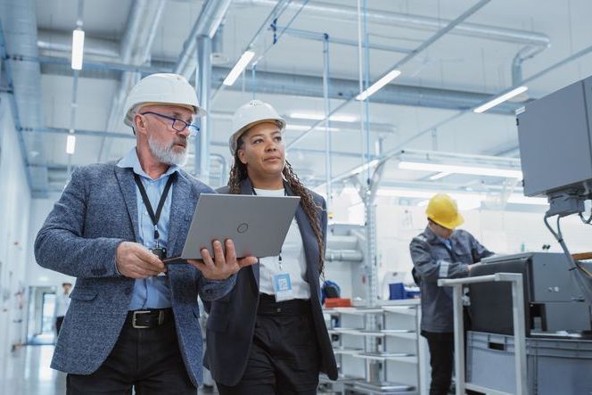 Two Professional Heavy Industry Engineers Wearing Hard Hats at Factory. Walking and Discussing something