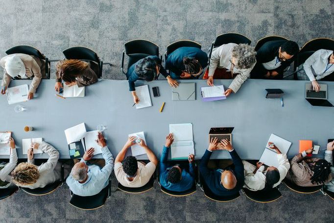 Top view of diverse business group in office meeting, collaborating and discussing around a large table.