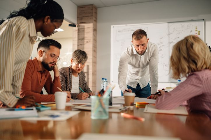 Diverse professionals collaborate in a modern office, led by their manager in a brainstorming session