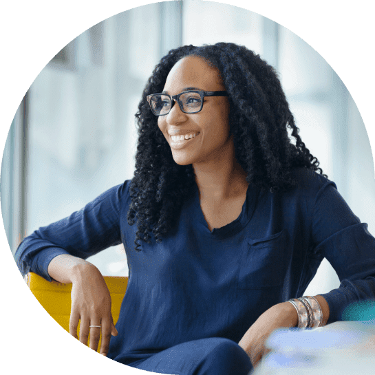 A black woman wearing glasses and sitting in an office.