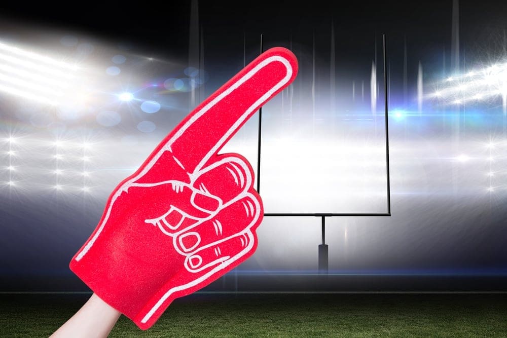 American football player holding supporter foam hand against american football arena.jpeg