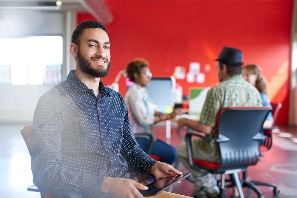 https://careerminds.com/wp-content/uploads/2023/09/Confident-male-designer-working-on-a-digital-tablet-in-red-creative-office-space.jpeg