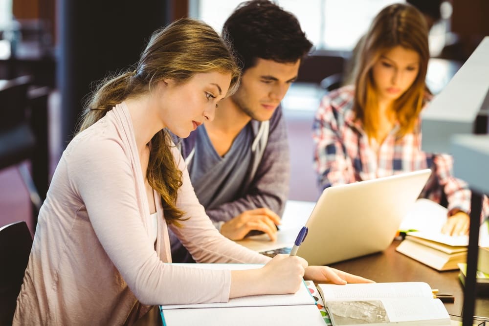 A group of students working on a laptop in a library.