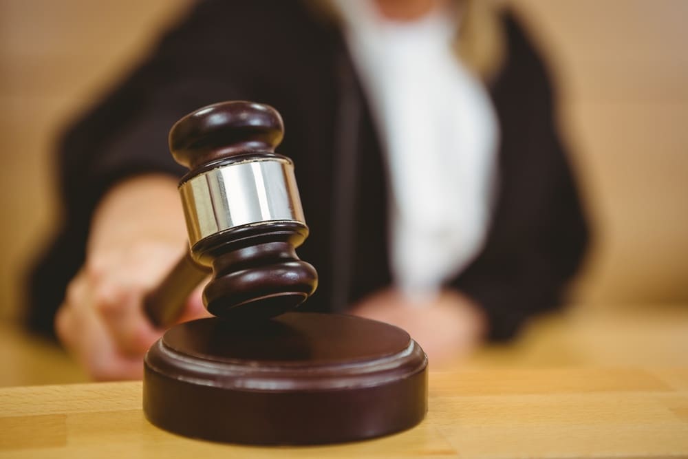 A woman is holding a gavel in a courtroom.