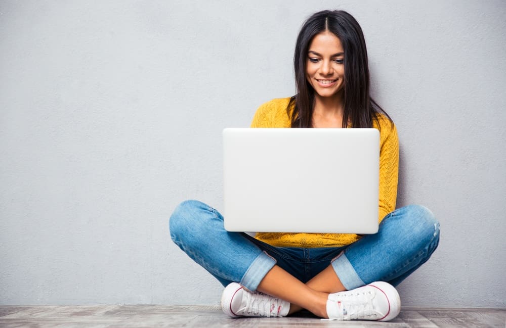 A young woman sitting on the floor with a laptop.