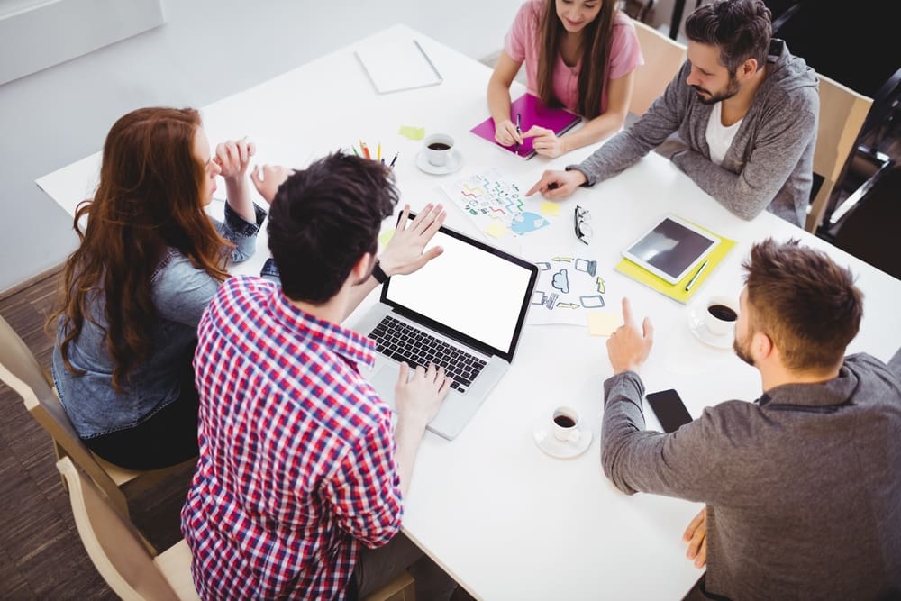 A group of people sitting around a table in a meeting.