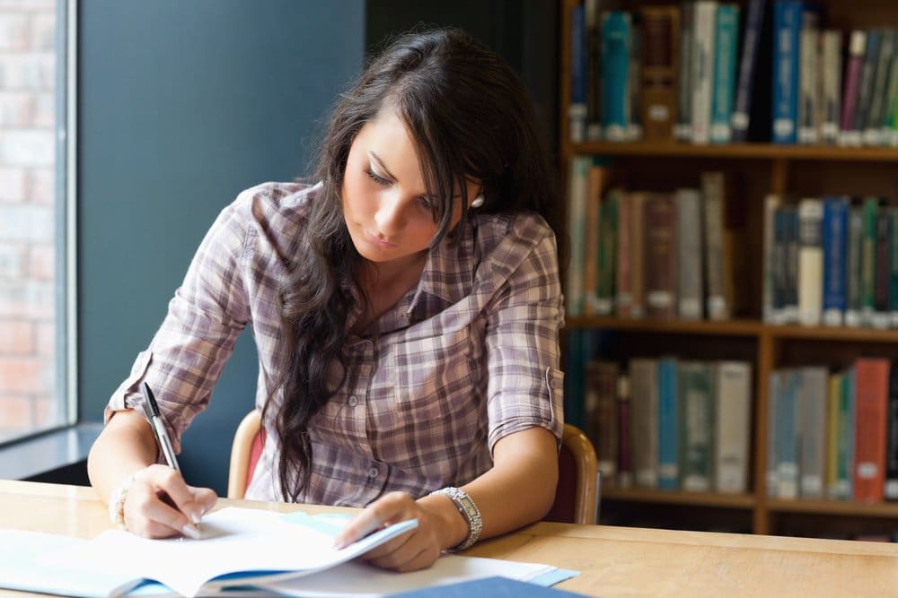 Young student writing in a library