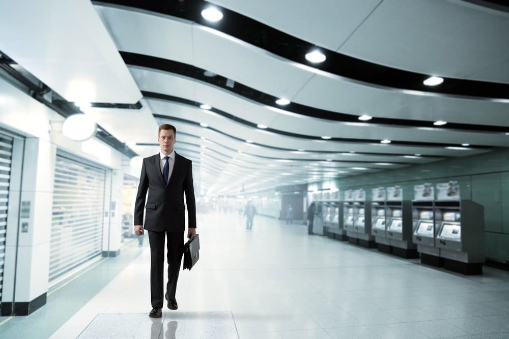 A businessman in a suit walking through a subway station.