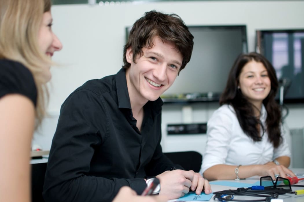 A group of people sitting around a table and smiling.