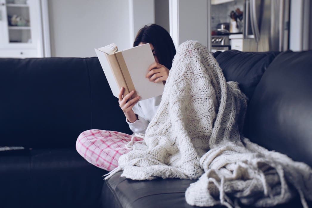 young-teenage-girl-sitting-on-a-couch-with-a-cozy-blanket-and-reading-a-book-nominated_t20_gRGj9d