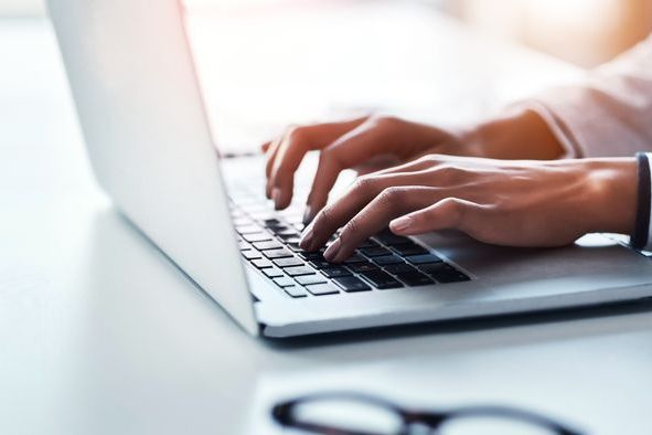 Hands of a woman typing on a laptop