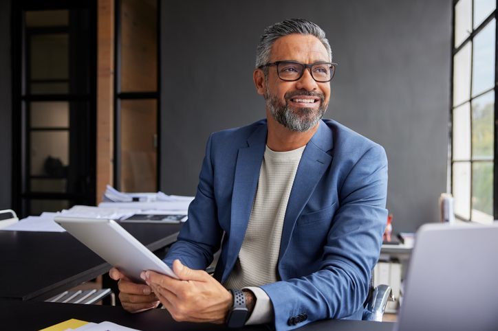 Smiling businessman using tablet while looking out of the window