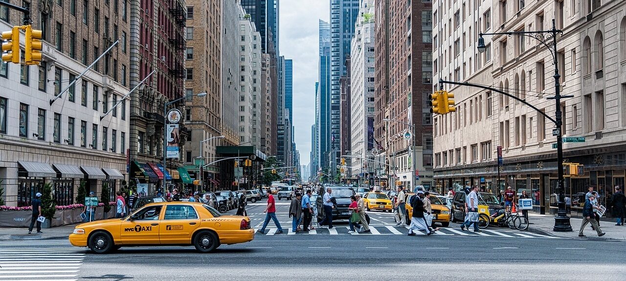 A city street with tall buildings and a yellow cab.