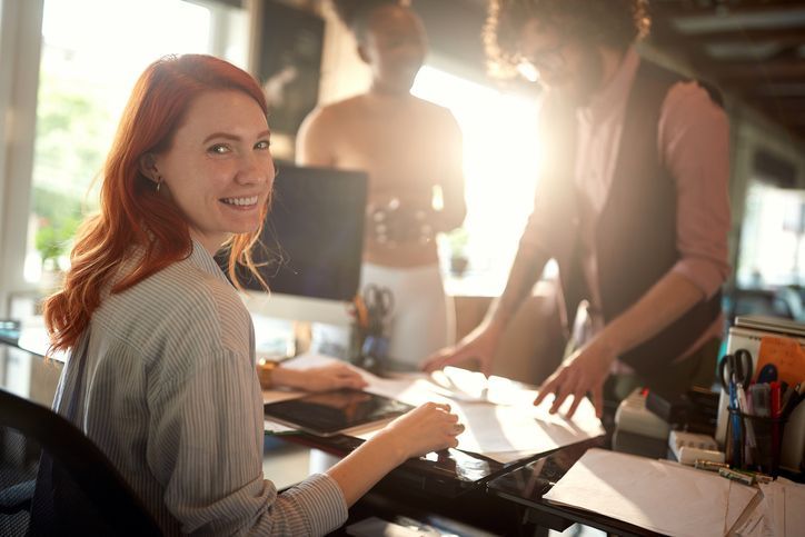 A new young female employee is posing for a photo at her new job in a pleasant atmosphere in the office
