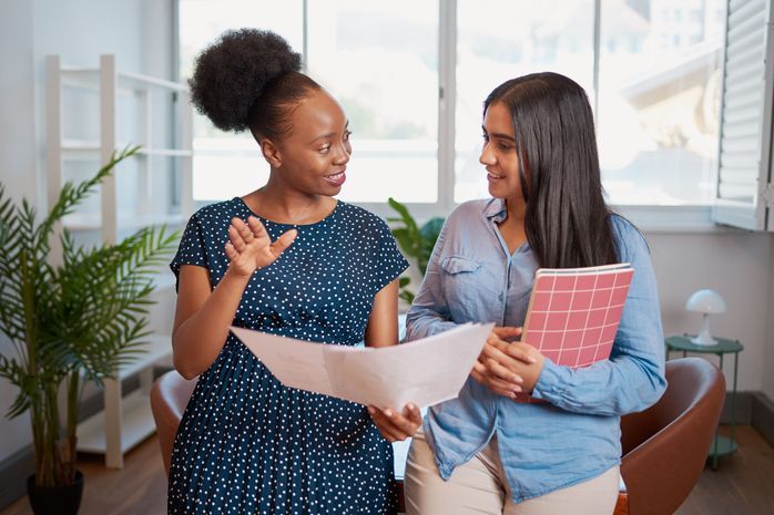 Two women discuss work solutions in boardroom office, mentorship learning. High quality photo