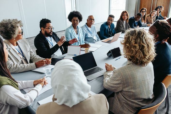 Multiethnic group of businesspeople engaged in a strategy and brainstorming session around a conference table. Collaborative and focused on teamwork and planning.
