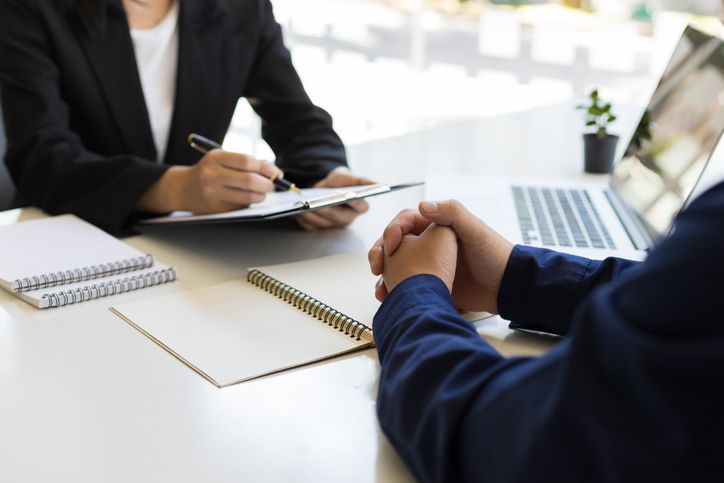 Two people discussing something, paperwork and a laptop on the table