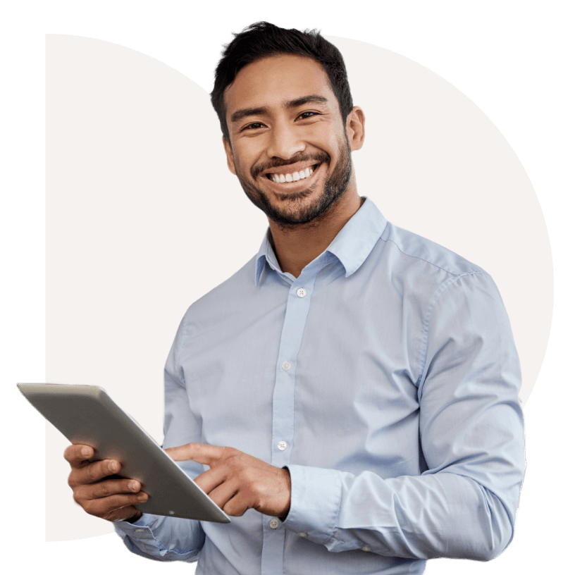 Man in a light blue shirt smiling, holding a tablet against a neutral background.