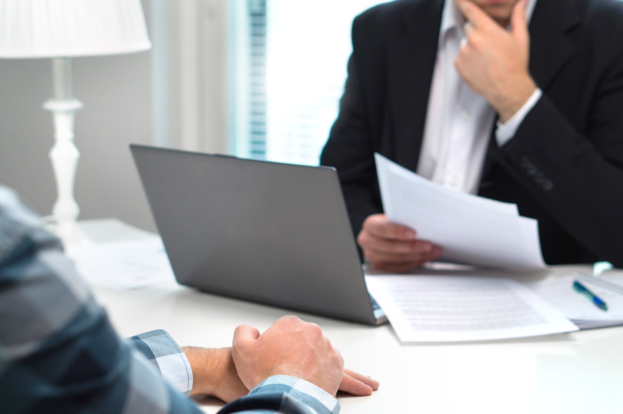 Layoff conversation between two people across a desk with some paper work.