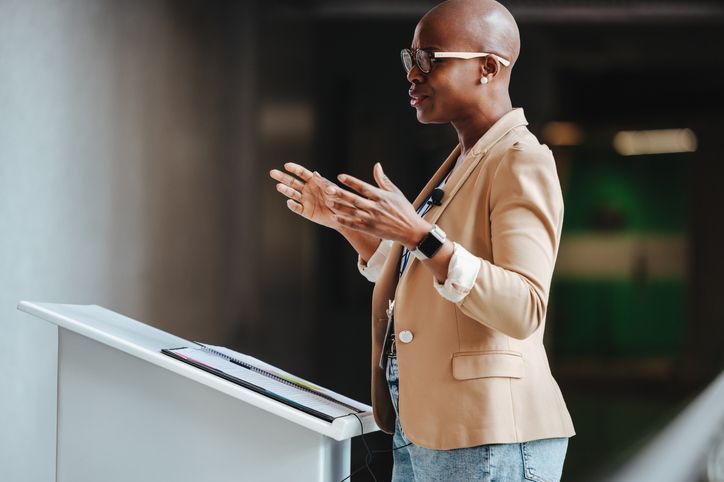 woman speaking in front of a stand